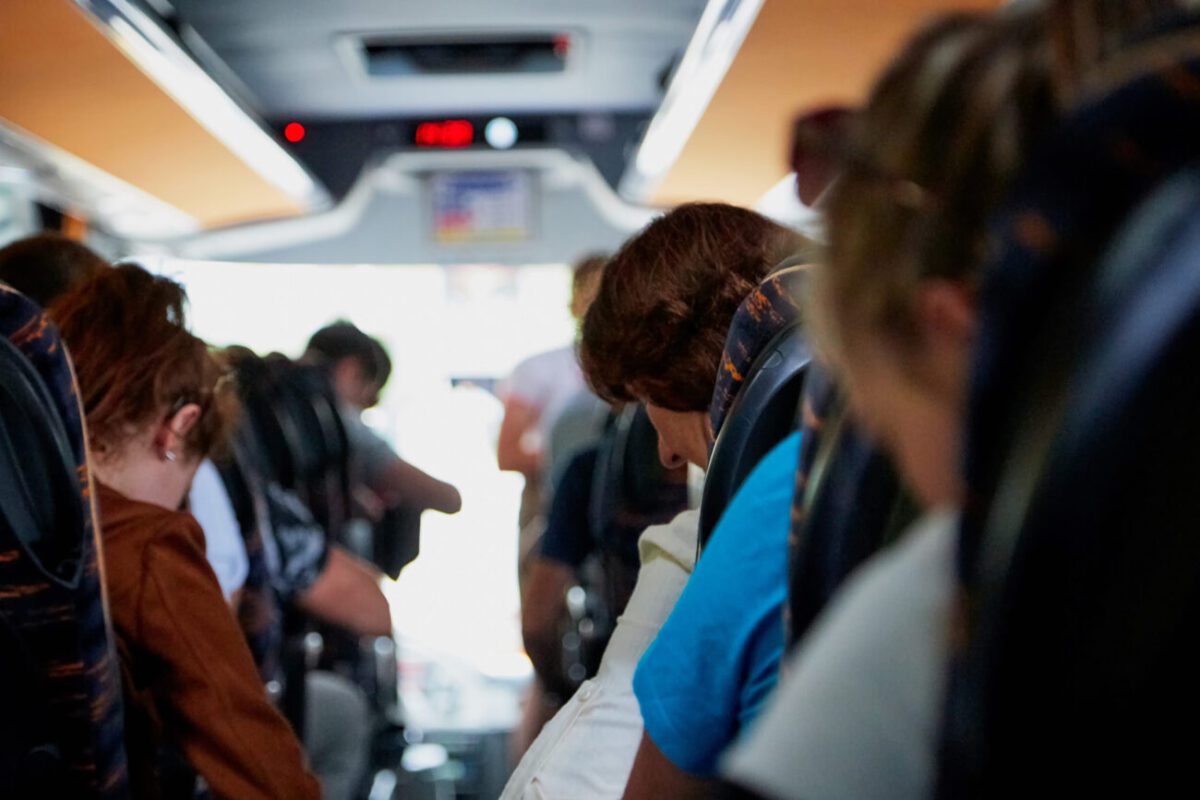 777469 Autocares Font | diario-economia.com Passengers seated on a bus aisle, some looking down or away, blur toward the front of the vehicle.