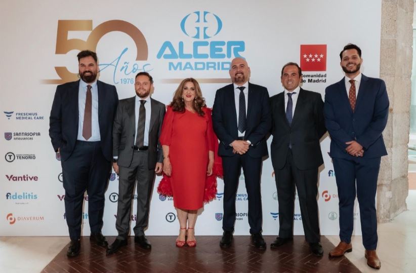 Six adults in formal attire posing for a group photo at an Alcer Madrid 50th anniversary event, backdrop shows logos and '50 Anos' text.