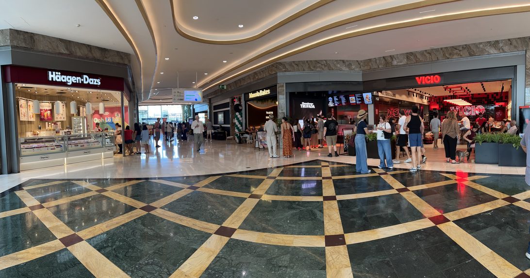Restauracion GP2 - IP | diario-economia.com Shoppers walk past Häagen-Dazs and VICIO stores inside a modern mall with a geometric tiled floor and curved lighting above.