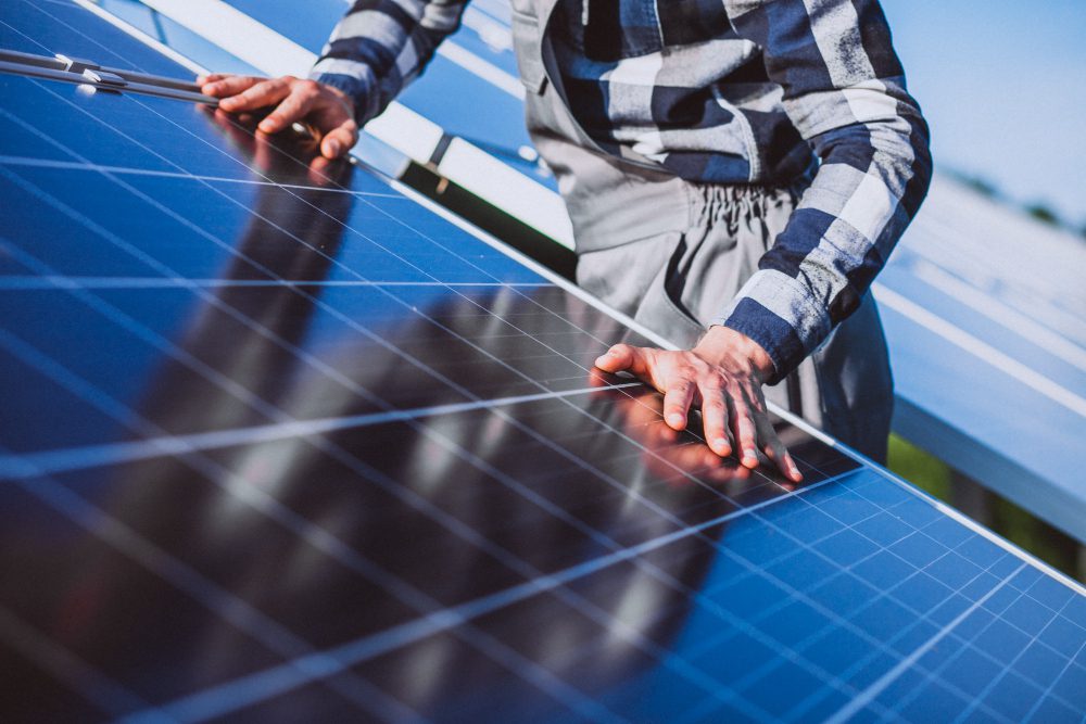 780498 - Fontlux | diario-economia.com Person in a plaid shirt touching solar panels, inspecting a photovoltaic array outdoors