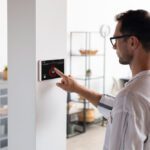 Man using a wall-mounted touchscreen control panel in a bright, modern home.