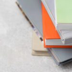 Stack of colorful books stacked diagonally on a light textured surface.