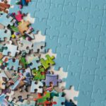 Scattered colorful puzzle pieces on the left with a mostly completed blue puzzle on the right side.