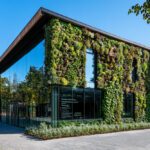 Modern glass-and-wood building with a living vertical garden on the façade.