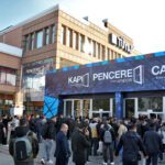Crowd of people gathered outside an exhibition hall with blue banners advertising PENCERE (windows) and CAM, inviting attendees to a glass and window trade show.