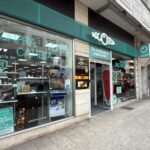 Storefront with teal signage advertising 'Compra Vende Cambia'; large glass window displays merchandise inside the shop on a city sidewalk.